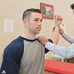 Male being assisted in stretches with his right arm.